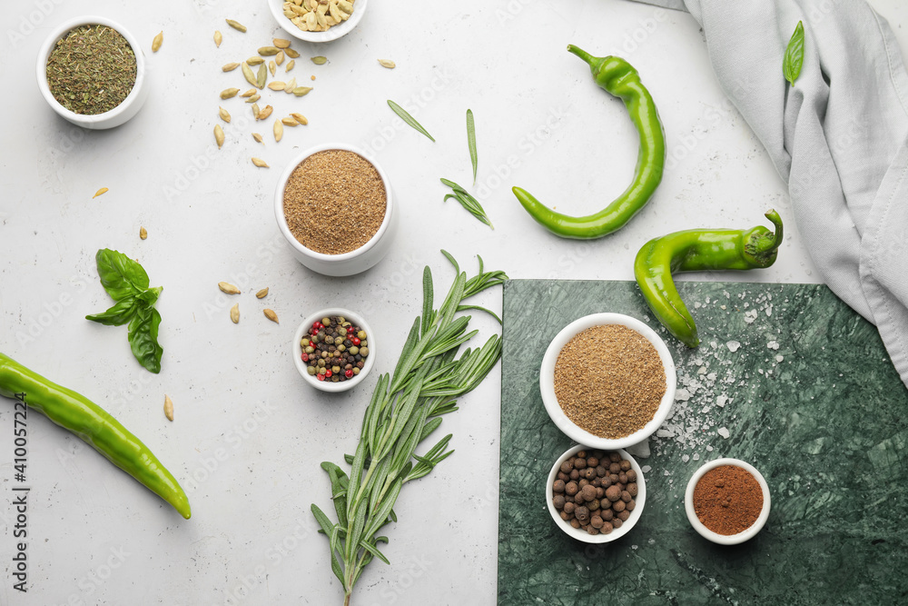 Board with different spices and herbs on light background