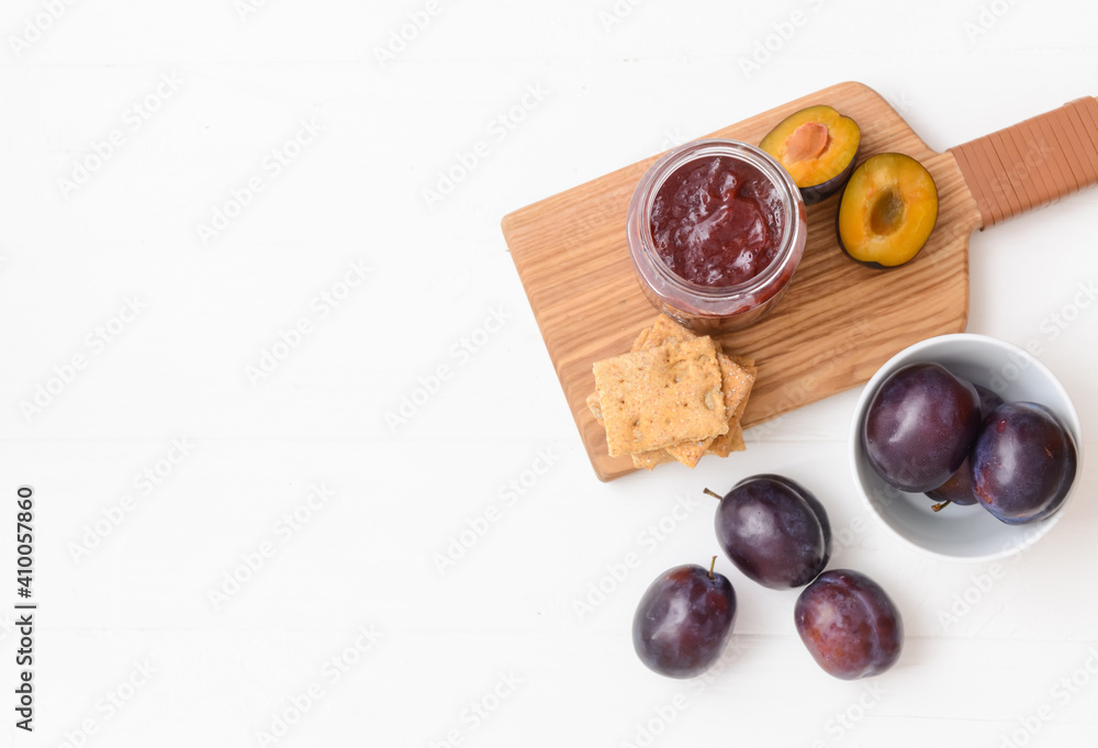 Glass jar with delicious homemade plum jam on white background