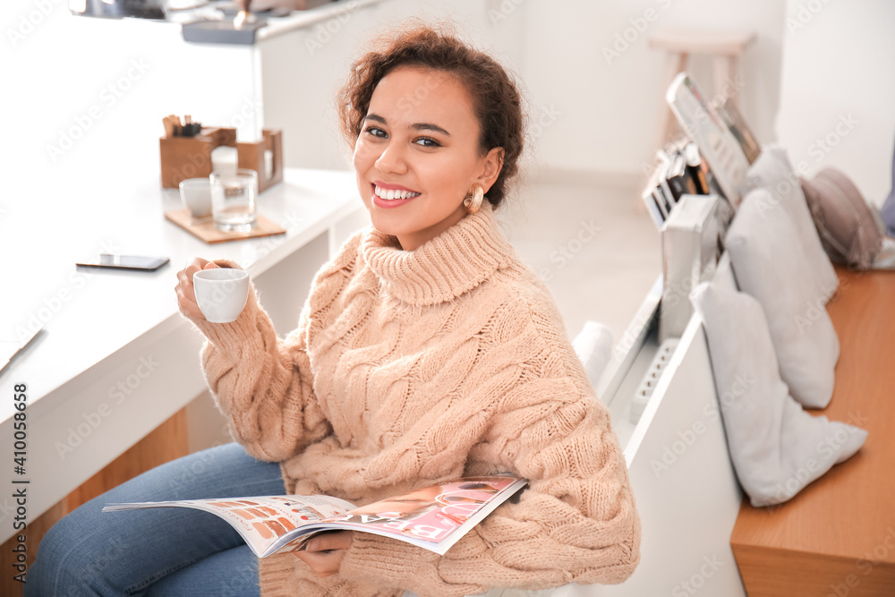 Beautiful woman with magazine and cup of hot espresso in cafe