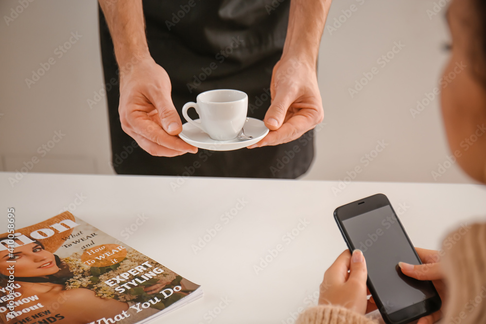 Barista bringing hot espresso for visitor in cafe