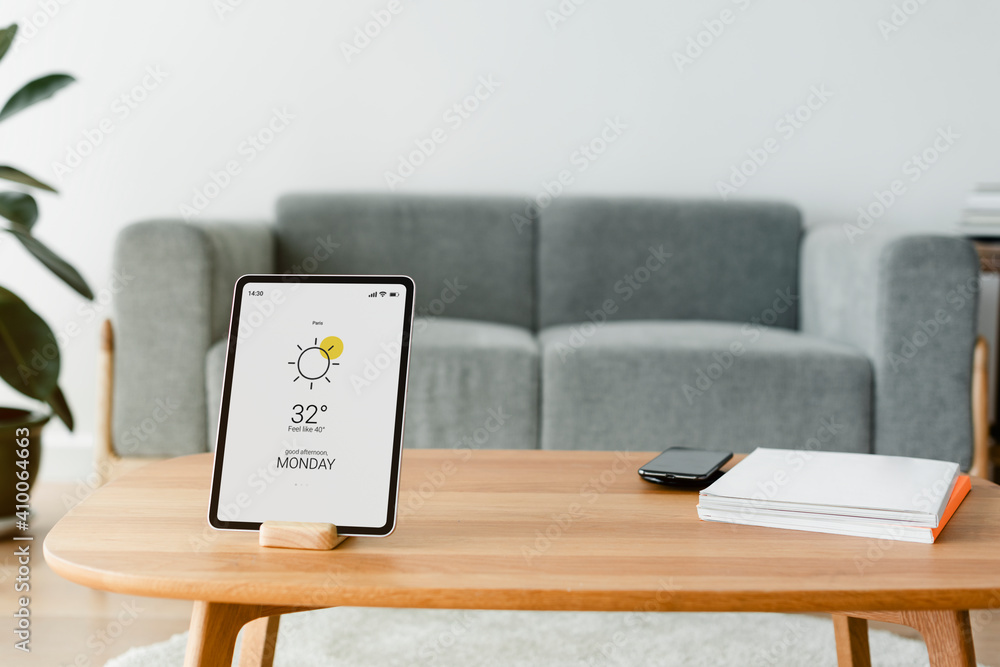 木制桌子上的带智能家居控制器的数字平板电脑屏幕