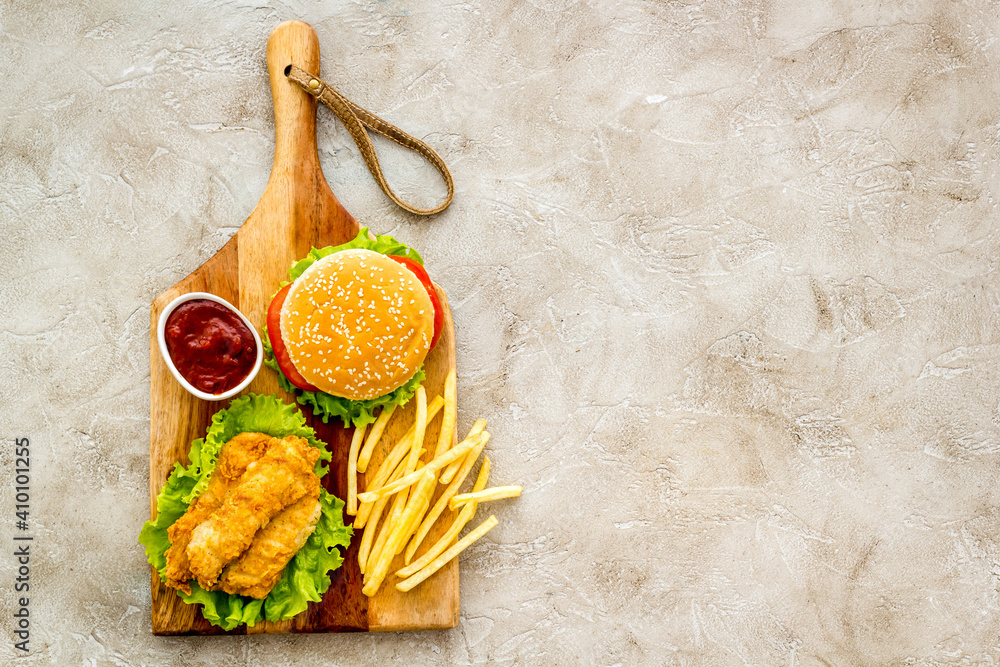 Fast food set. Delicious burger with french fries on wooden cutting board