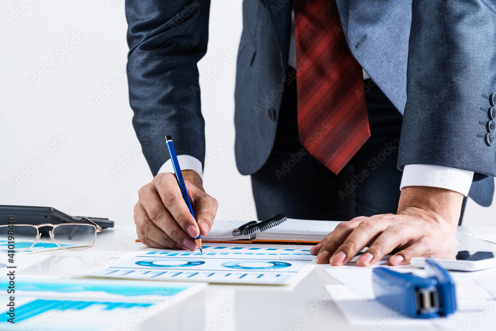 Businessman standing near office desk with pen