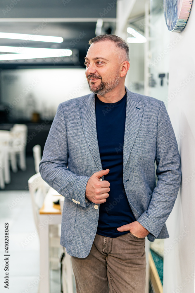 Portrait of handsome mature man holding hand in pocket with confident face. Blurred background. Busi