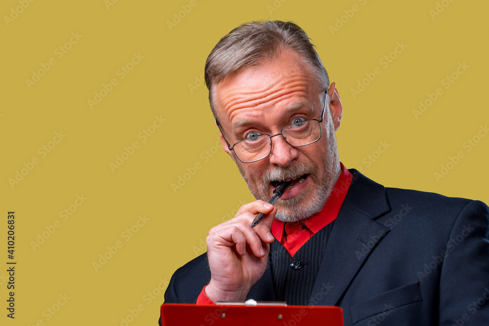 Portrait of a successful handsome businessman with red folder in hands. Mature man bites pen and loo