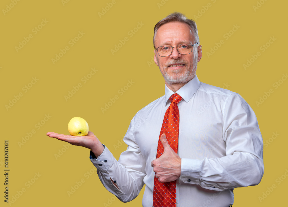 Portrait of a handsome senior man posing to the camera. Male is holding an apple in hand. Isolated o