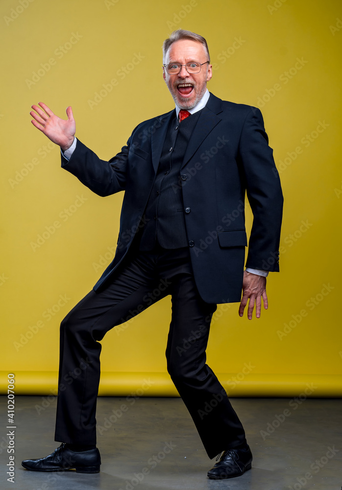 Senior manager man dancing at funny pose with expression. Yellow background.