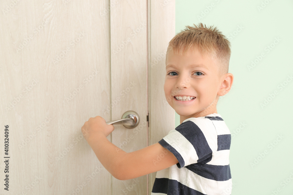 Cute little boy opening door in room