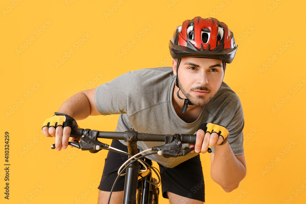 Male cyclist riding bicycle on color background