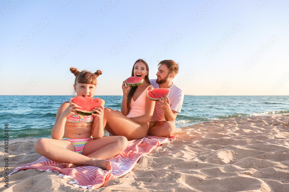 Happy family eating watermelon on sea beach