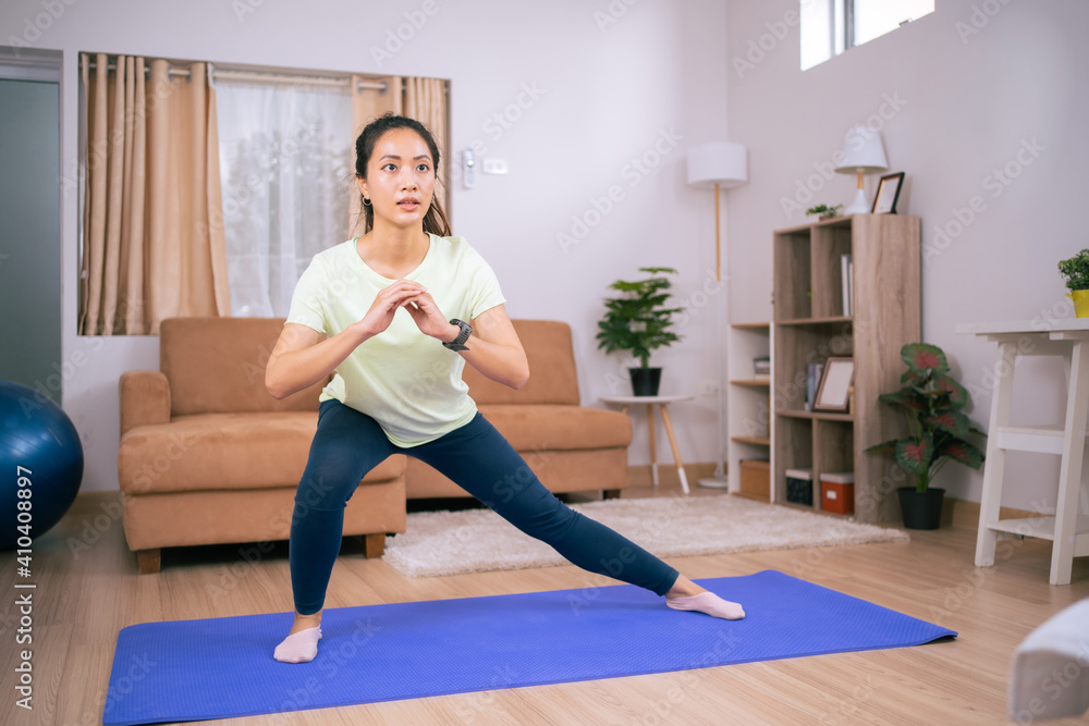 Beautiful Asian woman, she exercises at home, she does squats.