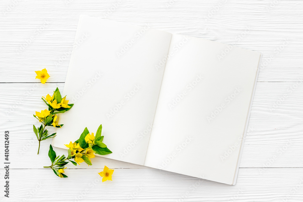 White paper blank with yellow spring flowers, overhead view