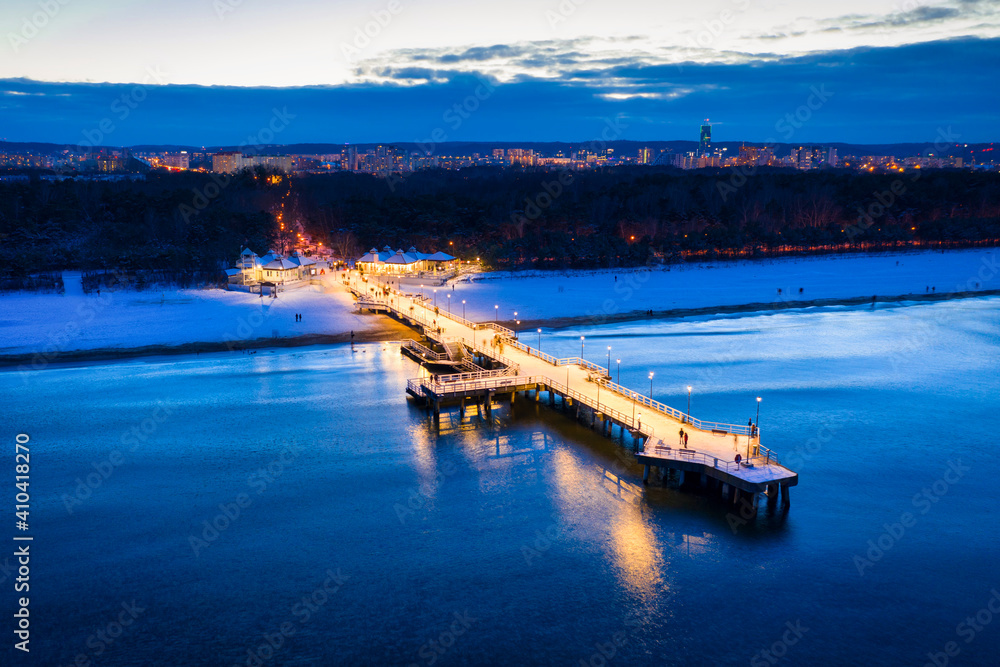 Illuminated pier in Brzezno on the winter beach at dusk, Gdansk.  Poland.