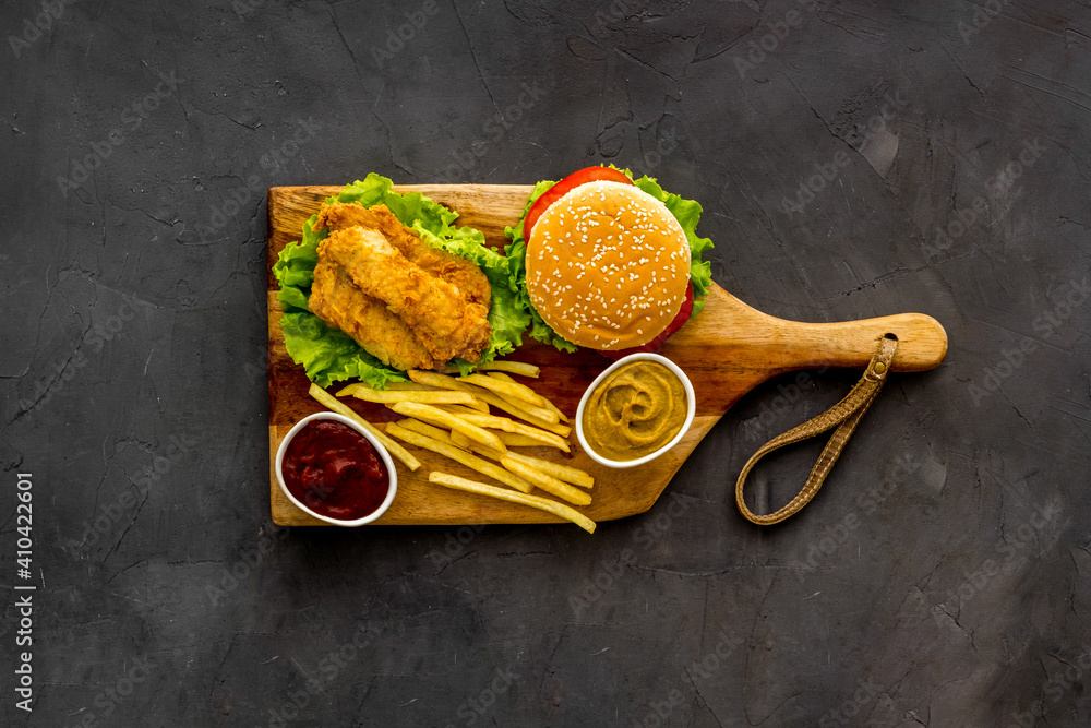 Fast food set. Delicious burger with french fries on wooden cutting board