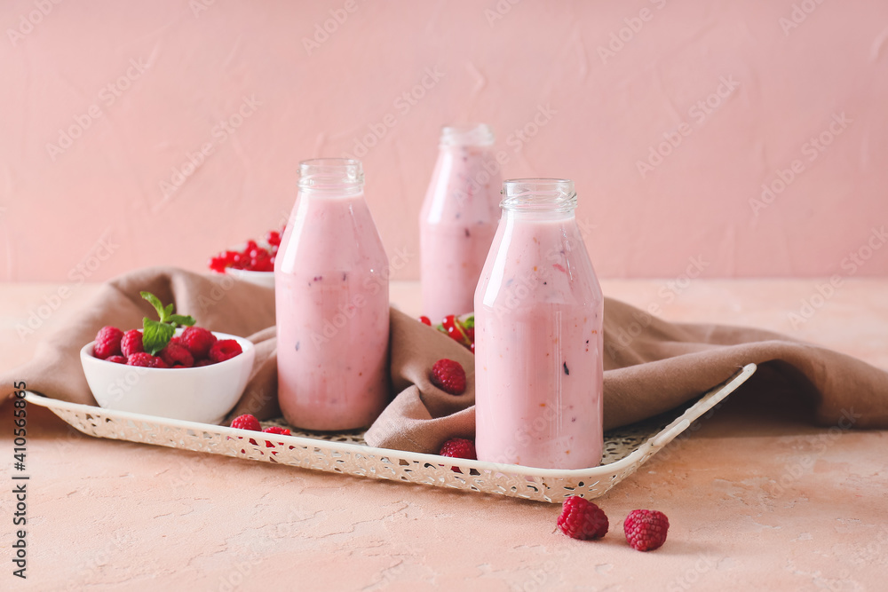 Bottles of smoothie with raspberry and cranberry on color background