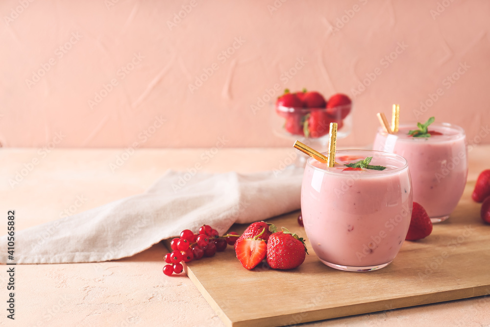 Glasses of tasty smoothie with strawberry and cranberry on wooden board