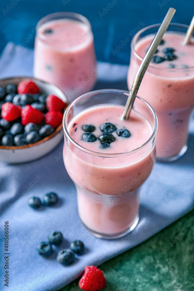 Glasses of tasty smoothie with blueberry and raspberry on color background