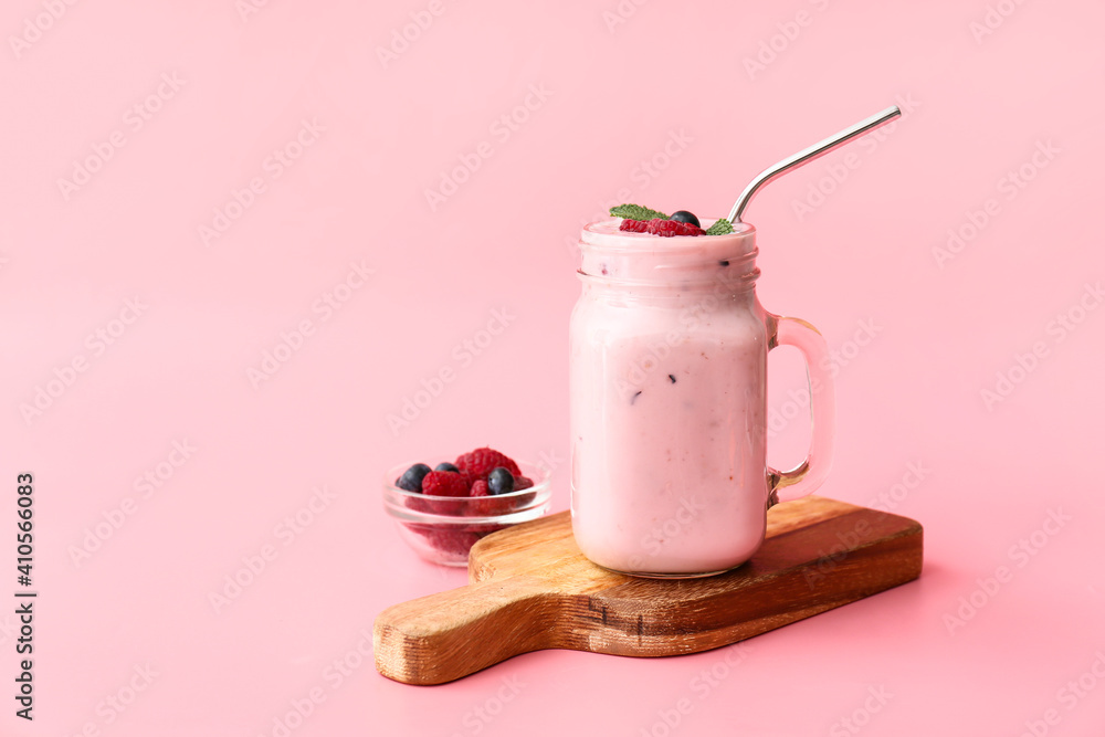 Mason jar of tasty smoothie with raspberry and blueberry on color background