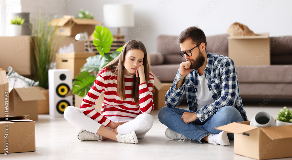 Tired couple unpacking boxes after relocation