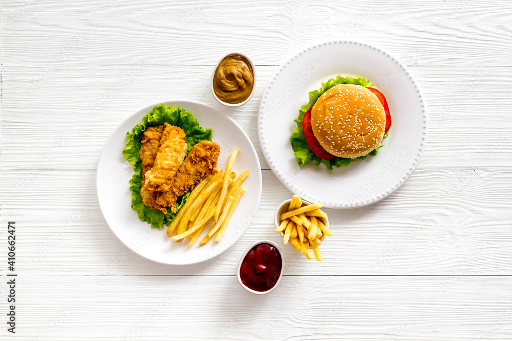 Burger with fried potatoes and chicken, top view