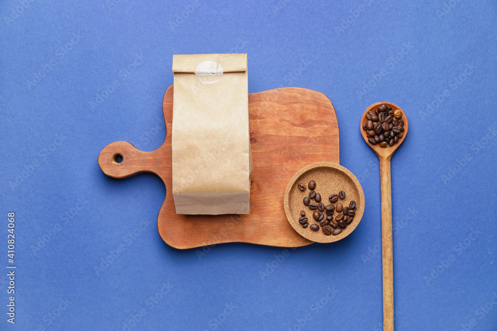 Paper bag with coffee beans on color background