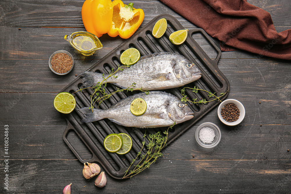 Raw dorado fish with ingredients on wooden background