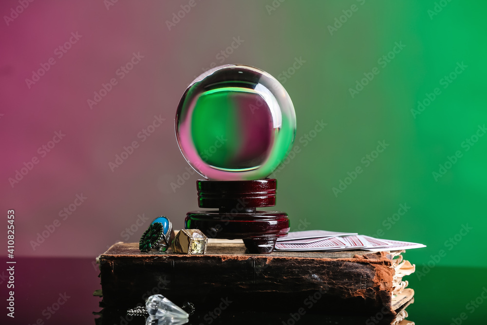 Crystal ball of fortune teller, old book and cards on table