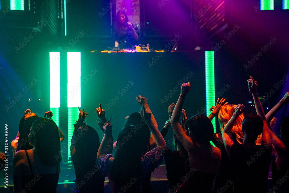 Silhouette image of people dance in disco night club to music from DJ on stage . New year night part