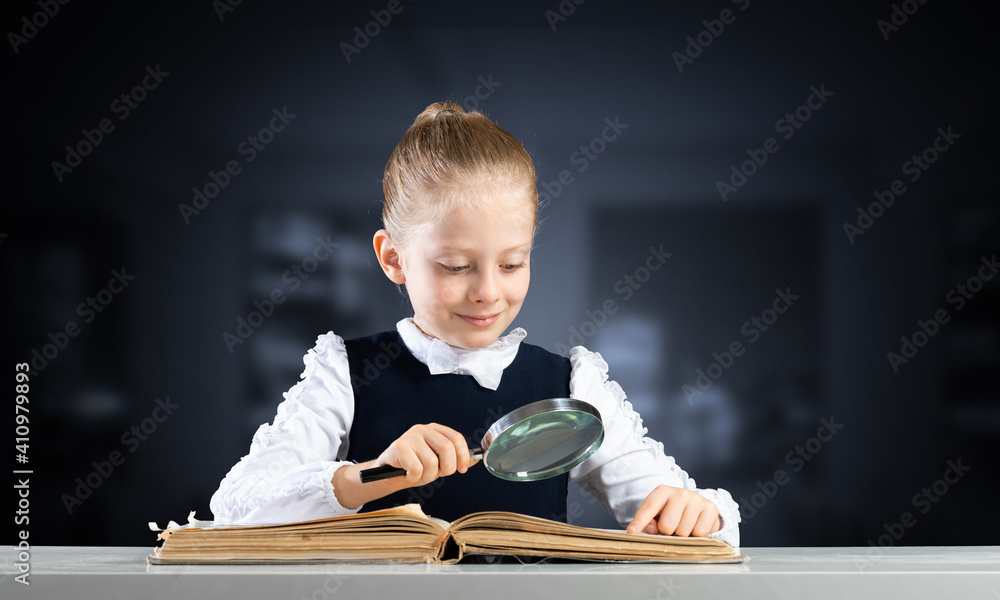 Little girl sitting at desk with magnifier