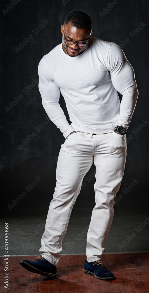 Full body portrait of funny cheerful african american in total white look over black background. Han