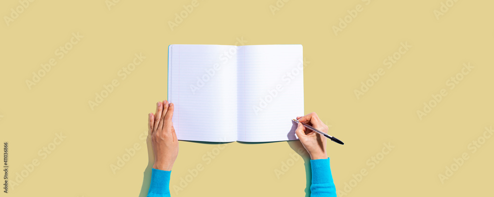 Person writing in a notebook from above