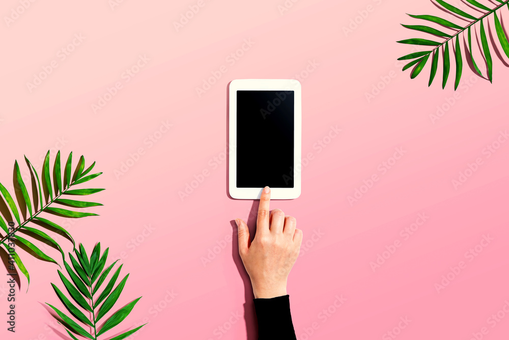 Person using a tablet computer with tropical leaves and shadow