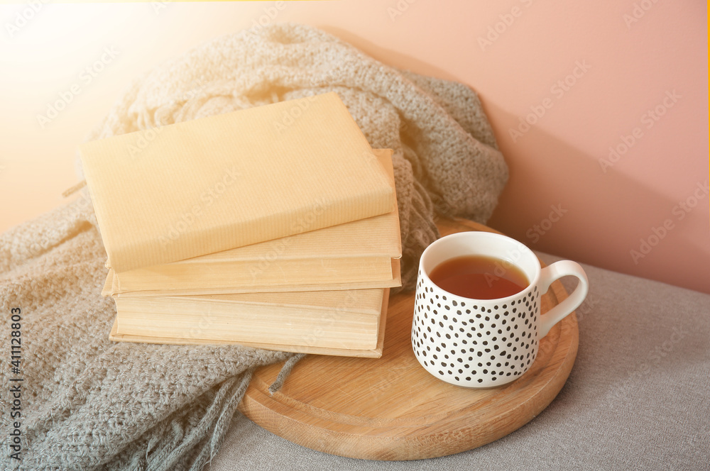 Books, warm plaid and cup of tea on bench