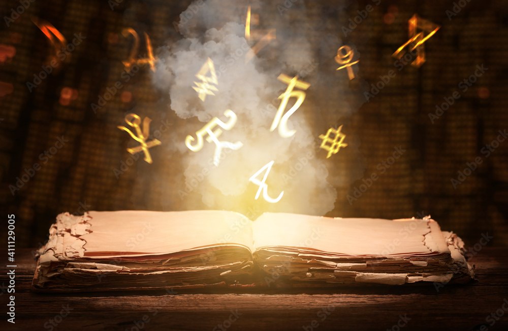 Old book and alchemical symbols on dark background