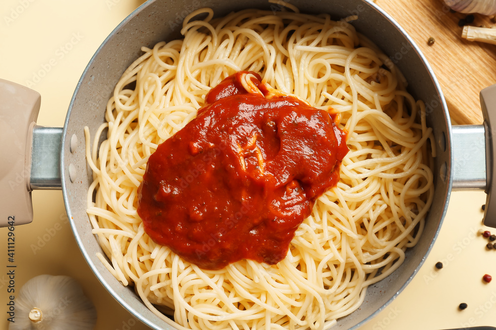 Cooking pot with pasta on color background