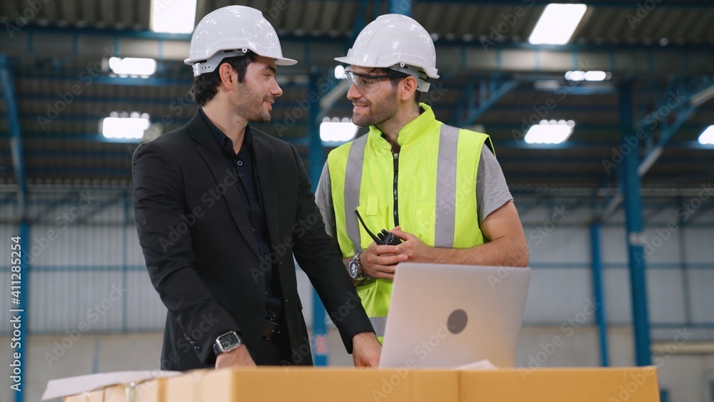 Two factory workers working and discussing manufacturing plan in the factory . Industry and engineer