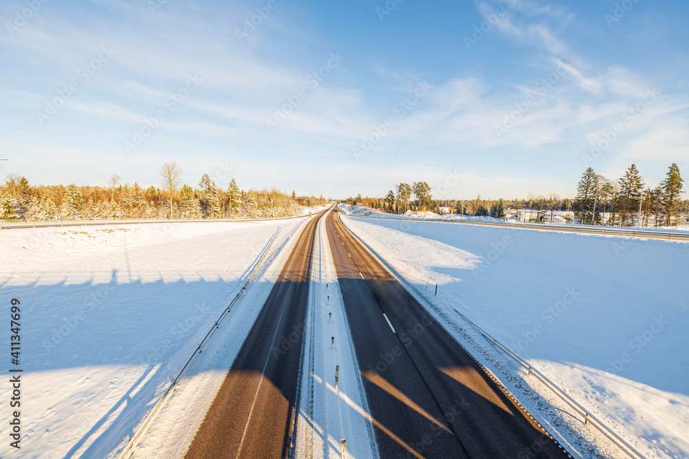 从冬季公路上俯瞰美丽的景色。边上的田野被雪覆盖，天空湛蓝