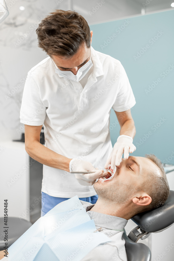 Young male patient with dental braces during a regular orthodontic visit. Dentist adjusting orthodon