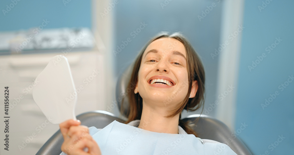 Portrait of a woman happy with her smile, looking out of the mirror during a dental visit. 4k video 