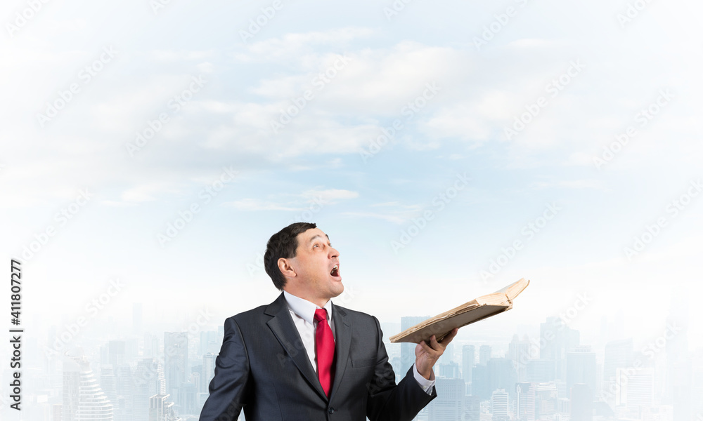 Surprised businessman holding open old book