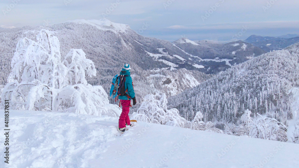 特写：一位女士在滑雪板前观察着令人惊叹的冬季景观。