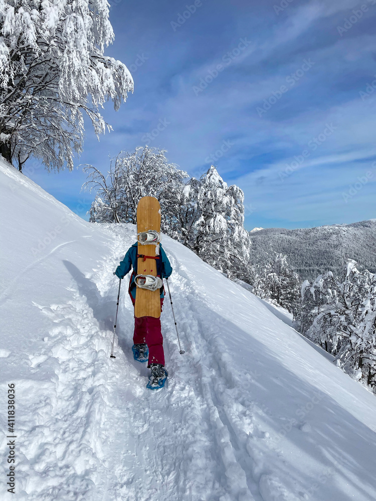 垂直：在晴朗的日子里，无法辨认的女单板滑雪运动员走上雪山。