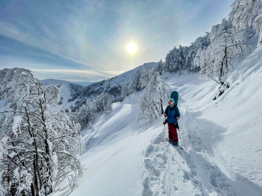 垂直：女单板滑雪运动员在穿雪鞋时观察冬季风景。