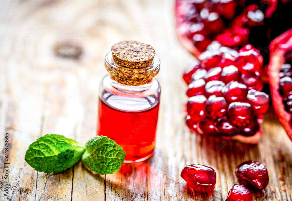 sliced pomegranate and extract in glass on wooden background