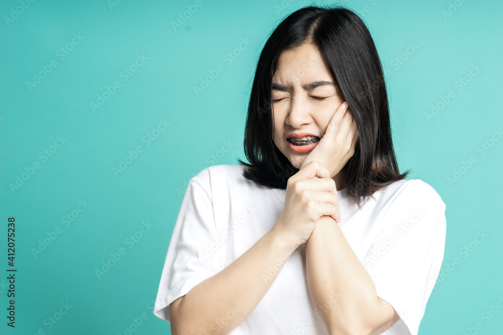 Teenage woman wearing braces and she is having a toothache isolate background