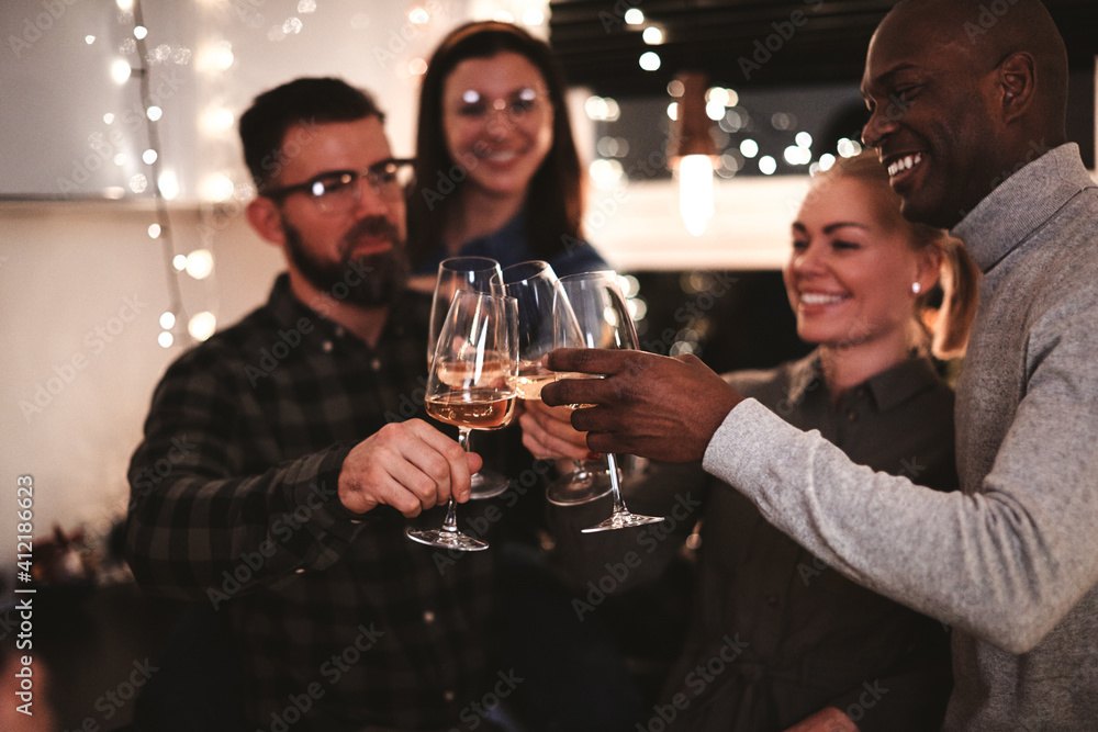 Smiling friends toasting with drinks during a dinner party