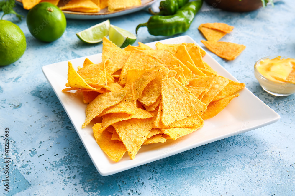 Plate with tasty nachos and sauce on color background, closeup