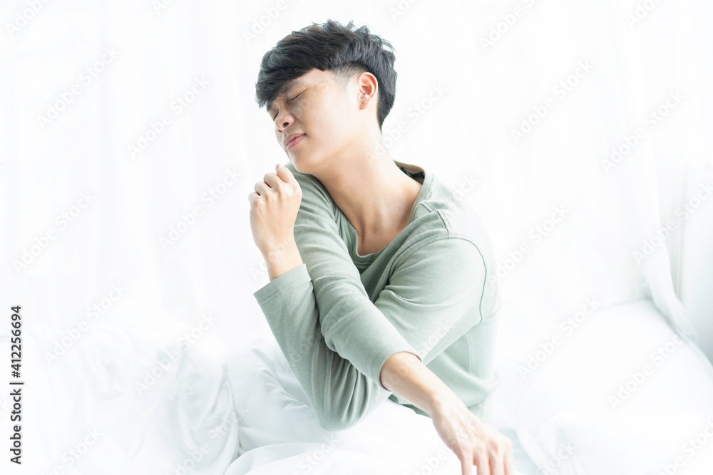 Young Asian man wakes up in bed one early morning