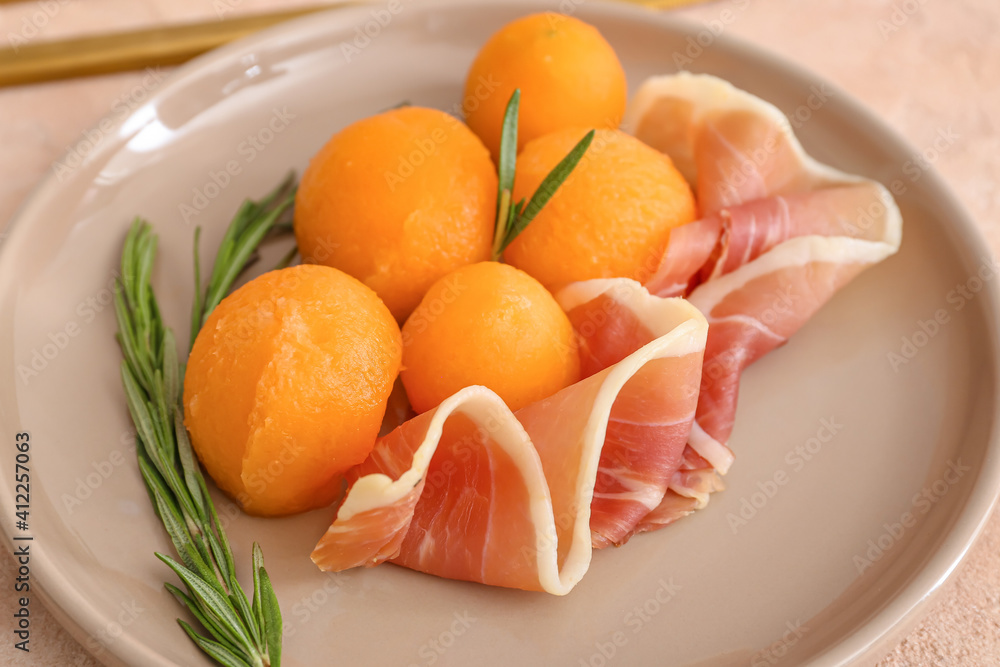 Plate with delicious melon and prosciutto on color background, closeup