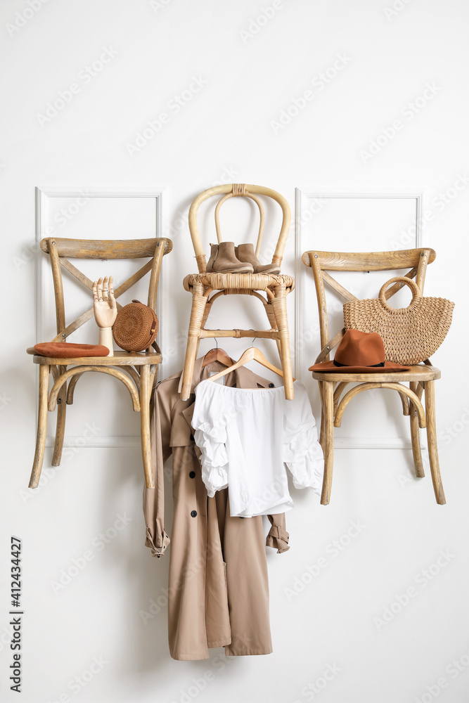 Chairs with clothes and accessories hanging on light wall in room